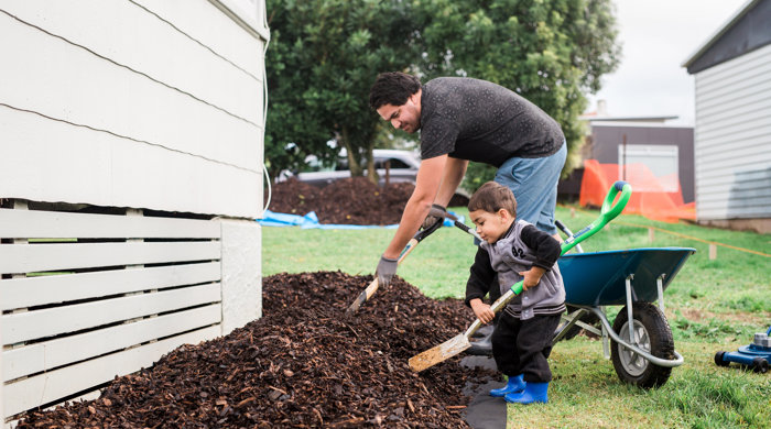 A man and boy are digging with spades in an urban garden.