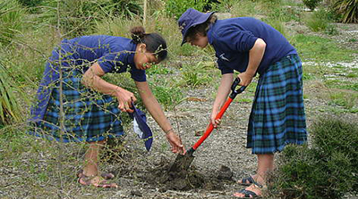 Two girls planting a seedling.